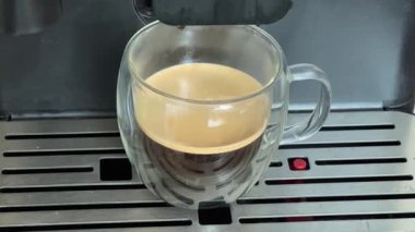 Cam bardakta otomatik kahve makinesiyle demlenmiş sıcak kahve.