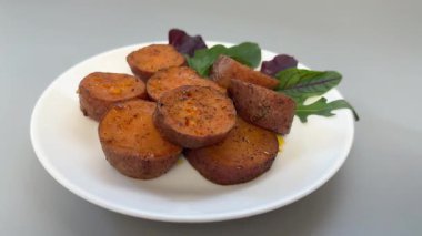 Pişmiş tatlı patates yumrusu tabakta daireler halinde dilimlenmiş.