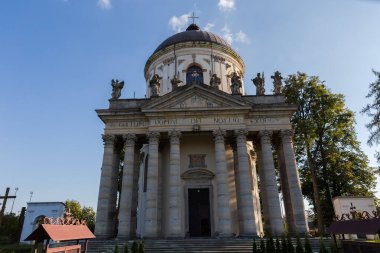 18. yüzyılın Barok Katolik Kilisesi 'nin ana cephesinde Ukrayna' nın Pidhirtsi köyünde güneşli bir akşamda Latince yazıtlar Tanrı 'yı yüceltiyor.