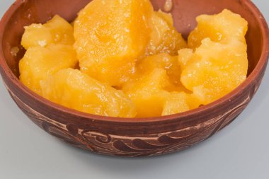 Kil kasede kristalize edilmiş beyaz bal parçaları gri arka planda, parça yakın plan.