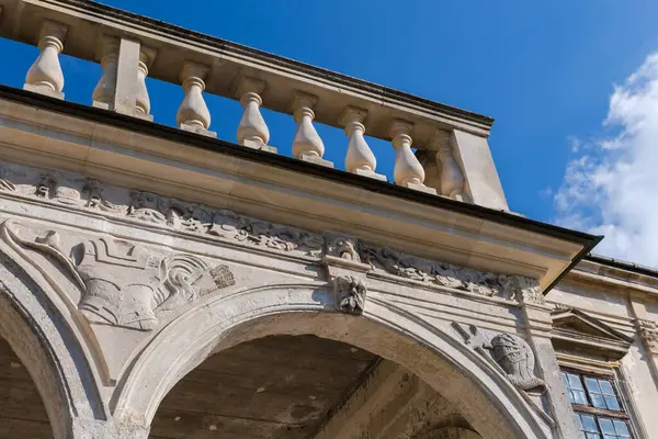 Güneşli bir günde ortaçağ şatosunun tepesinde, gökyüzüne karşı alttan bakan, oyulmuş hafif kumtaşından yapılmış eski kemerli galerinin üst kısmı.