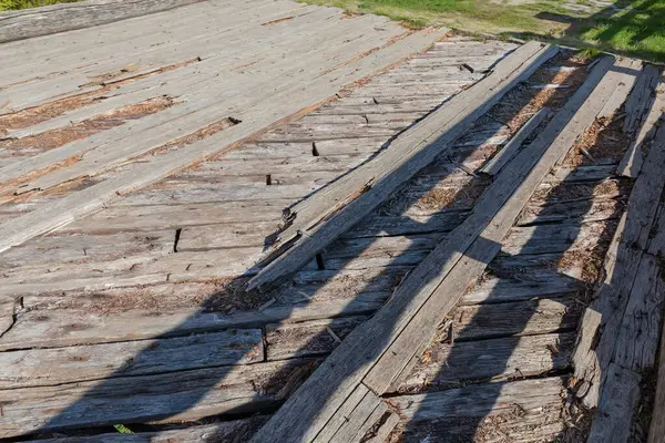 Eski ahşap köprünün kısmen harap olmuş güvertesinin bir parçası. Çürük kalaslar, güneşli bir günde, uzun bir süre yerleştirilmiş.
