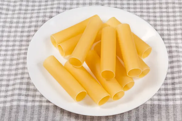 Çiğ yumurta tabanlı makarna, içi doldurulmuş yemekler için kabuk olarak tasarlanan, geniş silindirik tüpler şeklinde, masa örtüsüyle kaplı bir tabakta uzanıyor.