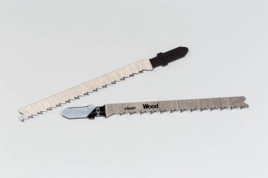 T- shanks ile elektrikli testere için iki testere, yüksek karbonlu çelikten yapılmıştır. Bacakları üzerinde temiz tahta kesikleri için HCS olarak adlandırılır. Gri bir arka planda yatar.