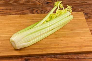 Köy tabakasındaki tahta kesme tahtasının üzerinde kesilmiş yaprakları olan taze kereviz sapları.