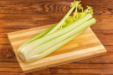 Köy tabakasındaki tahta kesme tahtasının üzerinde kesilmiş yaprakları olan taze kereviz sapları.