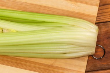 Tahta kesme tahtasındaki taze kereviz sapları, yakın çekim parçasının üst görüntüsü.