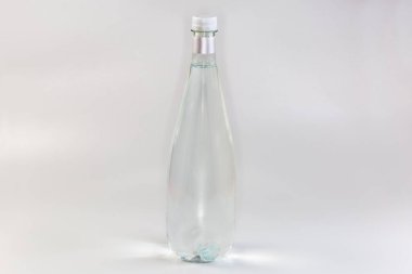 Plastik şeffaf maden suyu şişesi. Gri arka planda kapalı bir vida kapağı var. 