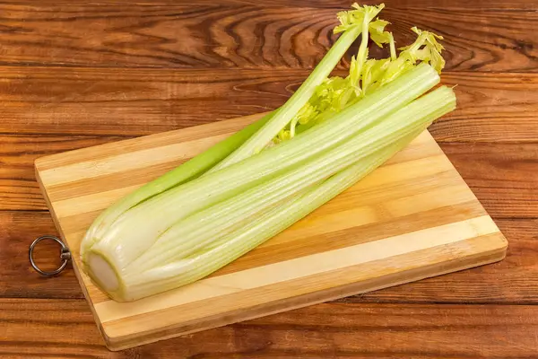 Köy tabakasındaki tahta kesme tahtasının üzerinde kesilmiş yaprakları olan taze kereviz sapları.