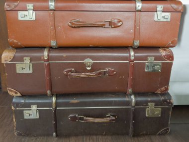 Stack of the closed old rectangular-shaped old-fashioned shabby hardshell suitcases made with leatherette of different color