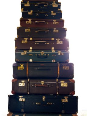 High stack of the closed old rectangular-shaped old-fashioned shabby hardshell suitcases different sizes, made with leatherette of various color on a white background backlit