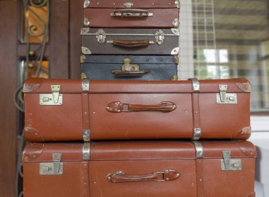 Stack of the closed old rectangular-shaped old-fashioned shabby hardshell suitcases different sizes, made with leatherette of different colors