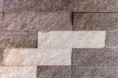 Binanın duvarının bir kısmı dikdörtgen gri taşlarla çevrili. Farklı renkler, pürüzlü ön yüzey, dekoratif desen, doku ve arkaplan.