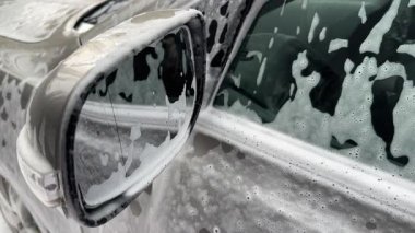 Araba kapısı ve dış ayna yıkanırken deterjanla kaplanmış.