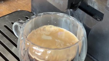 Kahve makinesiyle demlenmiş cam bardakta yakın plan kahve.