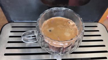 Kahve makinesiyle demlenmiş cam bardak, üst manzara.