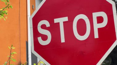 Ağaçlara ve bina duvarına yakın iki trafik işareti