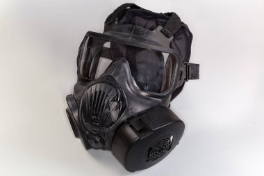 Gri bir arka planda maskenin yanına filtre takılmış siyah kauçuk gaz maskesi.