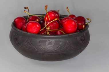 Koyu kırmızı kirazlar siyah klozetin saplarında gri bir arka planda, ön tarafta.