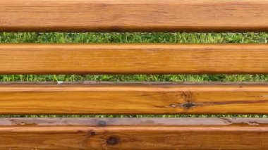 Verniklenmiş ahşap tahtalardan sırtı ıslak bankın bir parçası.