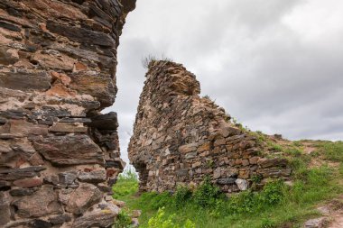 15. yüzyılın Hubkiv Kalesi 'nin taştan savunma duvarlarının bir kısmı yağmurlu bir günde bulutlu gökyüzüne karşı, Ukrayna
