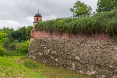 16. yüzyılın Dubno Kalesi 'nin derin hendeği ve küçük yuvarlak kulesi ile kale duvarının alt kısmı tuğladan ve üst kısmı bulutlu bir günde Ukrayna' da.