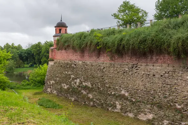 16. yüzyılın Dubno Kalesi 'nin derin hendeği ve küçük yuvarlak kulesi ile kale duvarının alt kısmı tuğladan ve üst kısmı bulutlu bir günde Ukrayna' da.