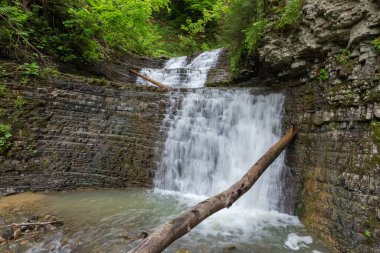 Zamlaksky şelalesi Ukrayna Karpatları 'nın katmanlı yapısına sahip üç kayalıktan düşüyor, bahar bulutlu gününde uzun çekimlerin alttaki görüntüsü