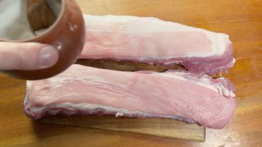 Tuz serpme sırasında tahtada çiğ domuz kaburgası.
