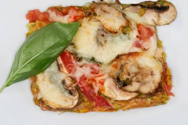 Beyaz tabakta taze yeşil fesleğen yaprağı ile süslenmiş tavuk eti ve mantarlı kabak hamurundan yapılmış bir pizza.