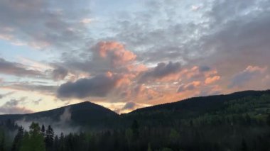 Ormanlı dağ sırası ve bulutlu gökyüzü gün doğumunda, zaman atlaması