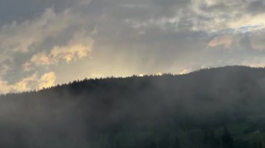Ormanlı dağ sırası ve bulutlu gökyüzü gün doğumunda, zaman atlaması
