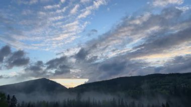 Ormanlı dağ sırası ve bulutlu gökyüzü gün doğumunda, zaman atlaması