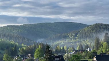 Güneşli bir sabahta bulutlu gökyüzüne karşı tepeler ve dağ köyleri