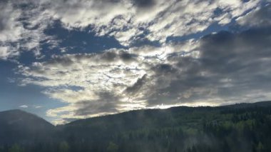 Güneşli bir sabahta, dağlık ve bulutlu gökyüzü