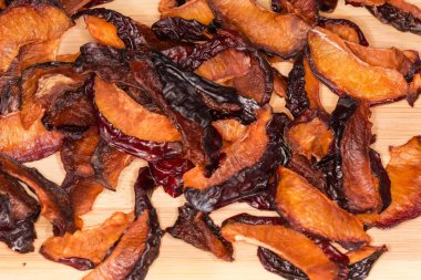 Ahşap bir yüzeyde kurumuş erik dilimleri, yakın plan.