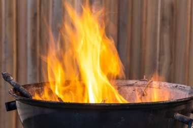 Terasta piknik için yanan siyah metal barbekü var.