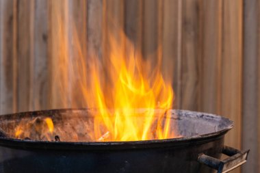 Terasta piknik için yanan siyah metal barbekü var.