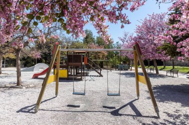 Yazın parkta bir salıncak, bir atlıkarınca, bir çocuk parkında bir kaydırak var.