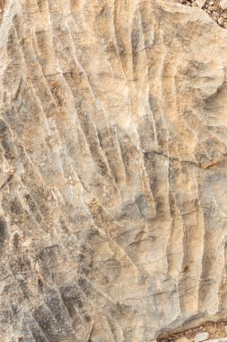 Gri ve turuncudan çatlaklarla kaplı eski bir taş duvarın güzel bir dokusu. Dikey fotoğraf