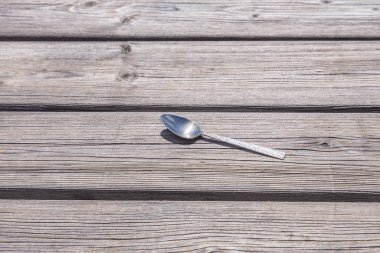 Metal kaşık gri ahşap arka planda.