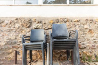 Turuncu ve sarı taşların üzerinde siyah plastik sandalyeler yığını