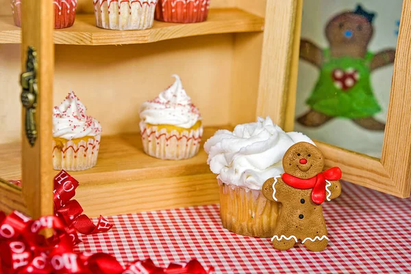 圣诞纸杯蛋糕放在木制橱柜里 上面有姜饼人的饼干和红白相间的姜黄纸片 — 图库照片
