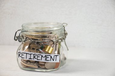 Coins and dollars in a glass retirement jar with a metal chain and padlock