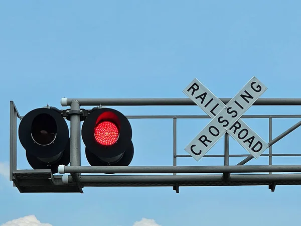 青い空に赤く点滅する光と鉄道の交差点標識 ストック画像