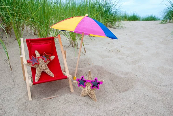海星在海滩上的红色躺椅上 戴着星形太阳镜 — 图库照片