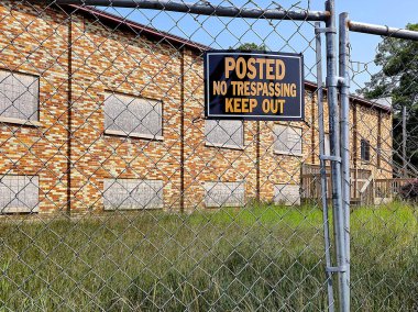 Terk edilmiş bir tuğla binayı çevreleyen tel örgülere izinsiz giriş işareti asılmamış. 