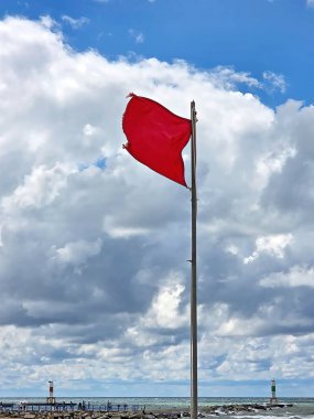 Arkaplanda Michigan Gölü olan dinamik ve bulutlarla dolu bir gökyüzünün zemininde canlı kırmızı bir uyarı bayrağı dalgalanıyor. 