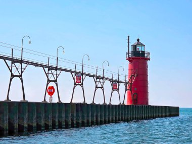 Michigan 'da canlı kırmızı bir South Haven deniz feneri bir rıhtımın ucunda dimdik duruyor, açık mavi gökyüzüne karşı. 