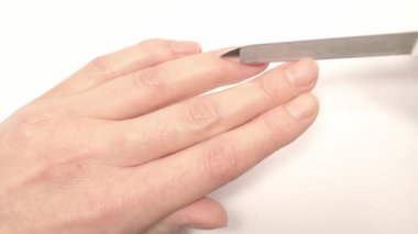 Tırnak şeklini metal bir tırnak törpüsüyle dolduruyorum. Çivilerin umurunda. Kadın çivileri metal bir tırnak törpüsüyle törpülüyor ve çivilerin yuvarlak şeklini alıyor. Görüntüyü kapat